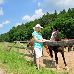 Frau mit Pferd am Zaun