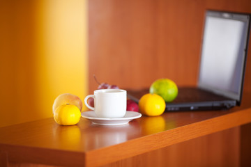 laptop,cup and fruits on the desk