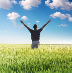 Fototapeta na wymiar man standing on the green field under blue sky