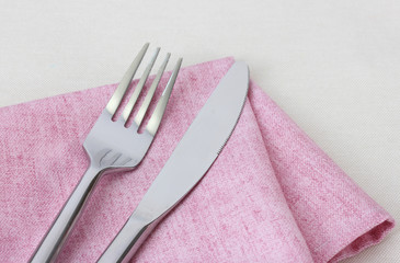 fork and knife on pink  napkin isolated on white