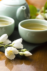 Plakat Zielona herbata z jaśminem w filiżance i czajniczek na drewnianym stole