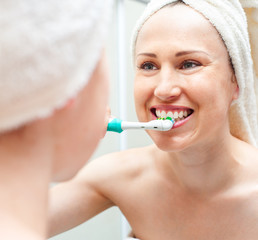 woman cleaning teeth near mirror
