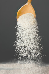 Wooden spoon with sea salt on a gray background close-up