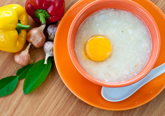 Rice porridge with egg in orange bowl.