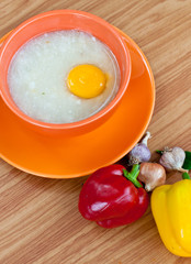 Rice porridge with egg in orange bowl.