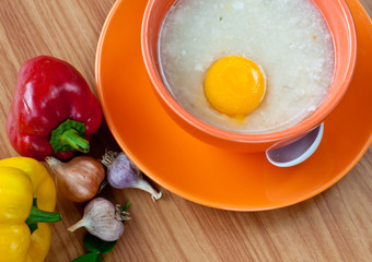 Rice porridge with egg in orange bowl.