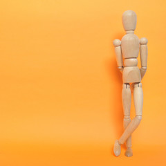 Holzfigur vor orange farbener Wand