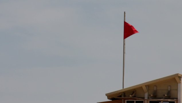 Red flag on the lifeguard booth on the beach