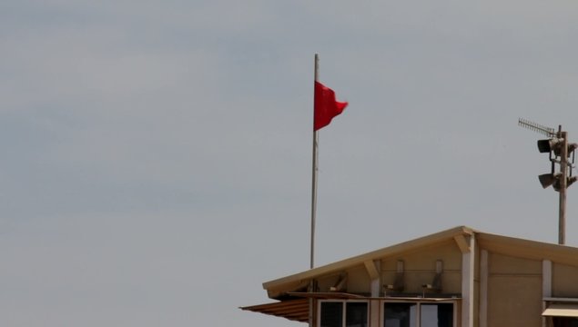 Red flag on the lifeguard booth on the beach