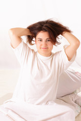 Happy young woman sitting in bed