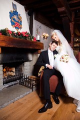 beautiful groom and bride  sitting near fireplace