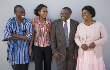4 Happy African people standing together against a wall