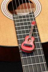 miniature guitar on the strings of an acoustic guitar