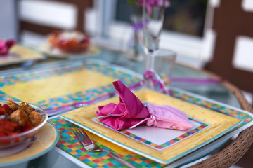 Table setting pink on balcony with fresh tomato salad