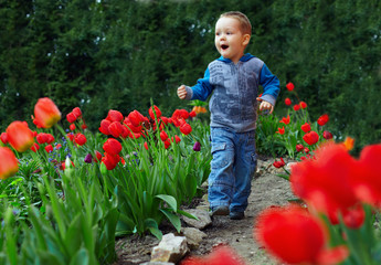 happy baby boy running the flower garden