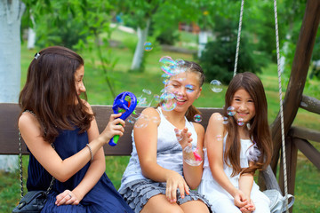 three beautiful teenage girls having fun blowing bubbles in summ