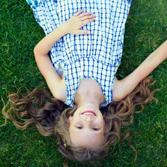 happy little girl having fun lying on green grass