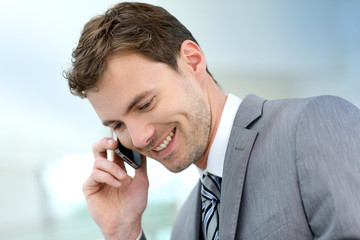 Smiling businessman having a phonecall in building hallway