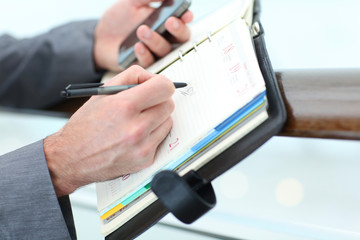 Closeup of businessman hand writing on agenda