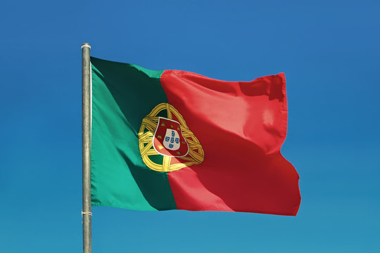 Portuguese flag and pole flutters against Portugal blue skies