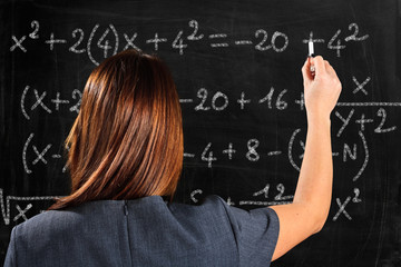 Woman writing a math formula on a blackboard © Minerva Studio