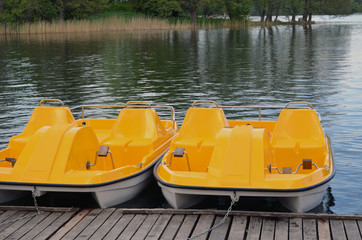 Yellow water bicycles locked at lake pier