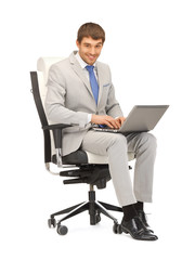 young businessman sitting in chair with laptop