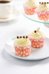 Cream cupcakes with chocolate decoration and tea.
