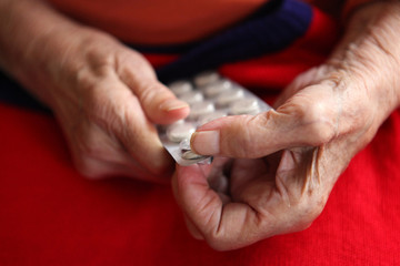 Close up of old hands with tablets.