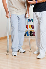 Man Holding Crutches Standing By Trainer