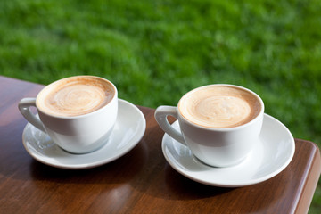 two cups of cappuccino on wooden table