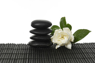 Black massage stones stacked with white Gardenia flower