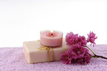 Obraz na płótnie Canvas spa set-candle on soap with plum flower on pink towel