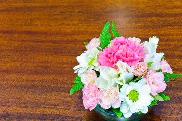 Assorted flowers in a glass vase on wooden table