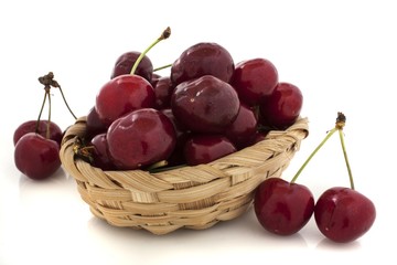 cherries spilling out from the basket on white background