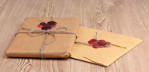 Parcel and envelope with sealing wax on wooden background