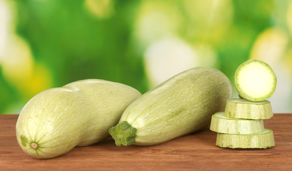sliced squash on wooden table on green background