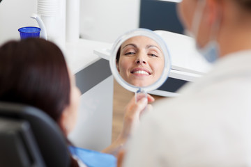 patientin beim zahnarzt lächelt in den spiegel