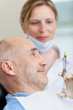 patient beim zahnarzt schaut auf spritze