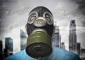  businessman with gas mask and city in the background, wide angle view. concept of defense against...