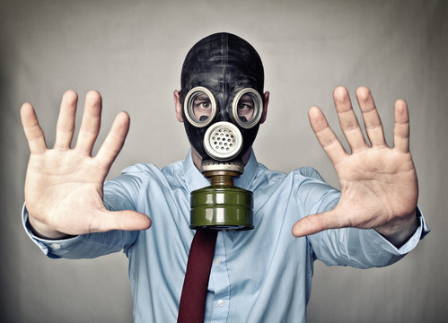  businessman with gas mask with big filter, hands forward and open as a sign of danger. concept of prevention from bacterial diseases and defense against viruses.