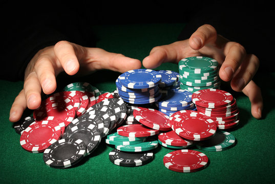 Poker chips and hands above it on green table