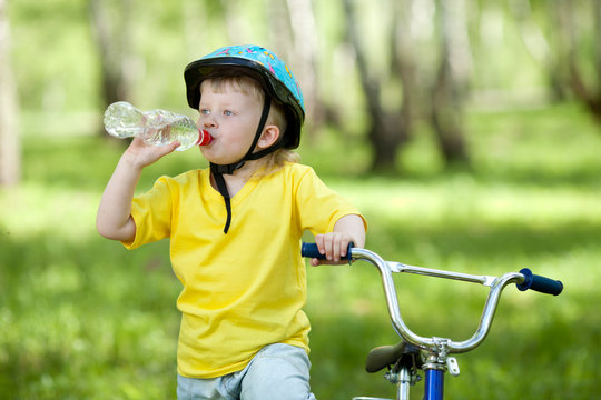 Cute Child Kid On Bicycle And Drinking  Water Fom Bottle