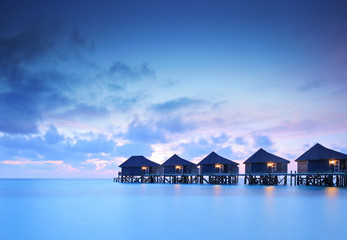 Water villa cottages at sunset on island of Kuredu, Maldives