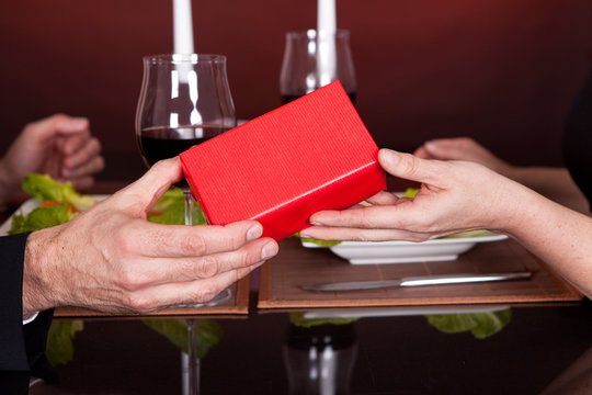 Man giving present to a woman in restaurant