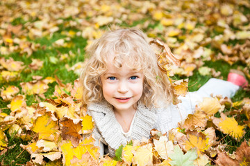 Child lying on autumn leaves