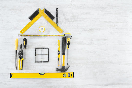 Tools In The Shape Of House Over Wooden Background. Home Improve