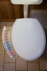 Euroscheine unter einem Toilettendeckel