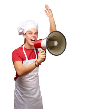 portrait of young cook man shouting with megaphone over white ba