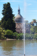 palm trees, trees and a fountain against the blue sky